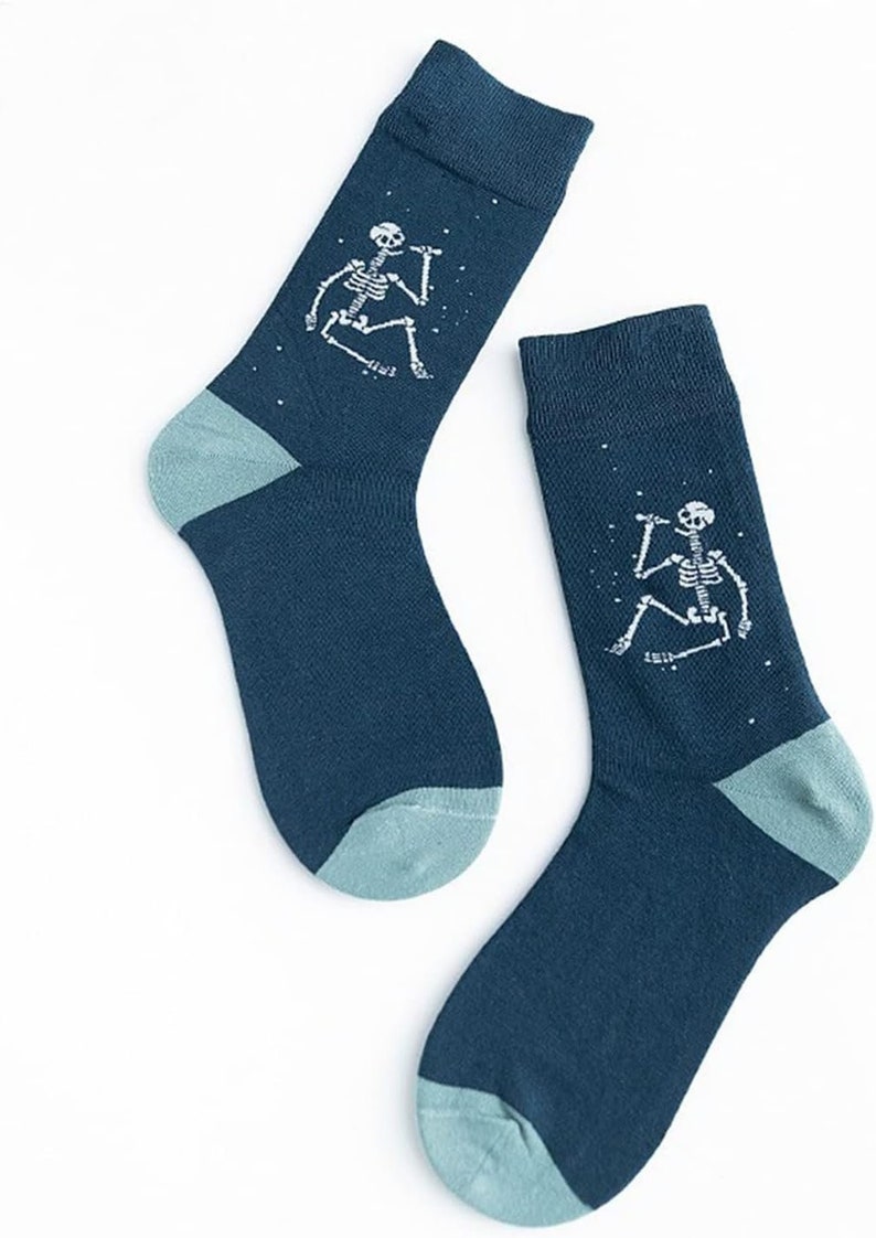 Puede incluir: Un par de calcetines azul oscuro con talones y dedos de los pies de color verde azulado claro. Cada calcet&iacute;n presenta un gr&aacute;fico de esqueleto blanco con un micr&oacute;fono, rodeado de peque&ntilde;os puntos blancos. Los calcetines probablemente est&aacute;n hechos de un material suave y c&oacute;modo.