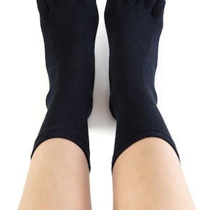 May include: A pair of black toe socks with five individual toe compartments. The socks are worn on a person's feet.