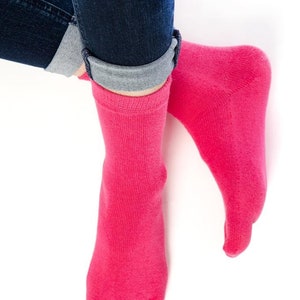 May include: A pair of pink toe socks with five individual toe compartments. The socks are made of a soft, stretchy material and are worn on a person's feet.