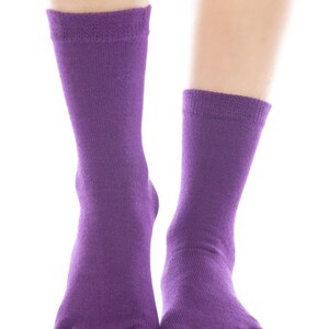 May include: A pair of purple toe socks with five individual toe compartments. The socks are made of a soft, stretchy fabric.