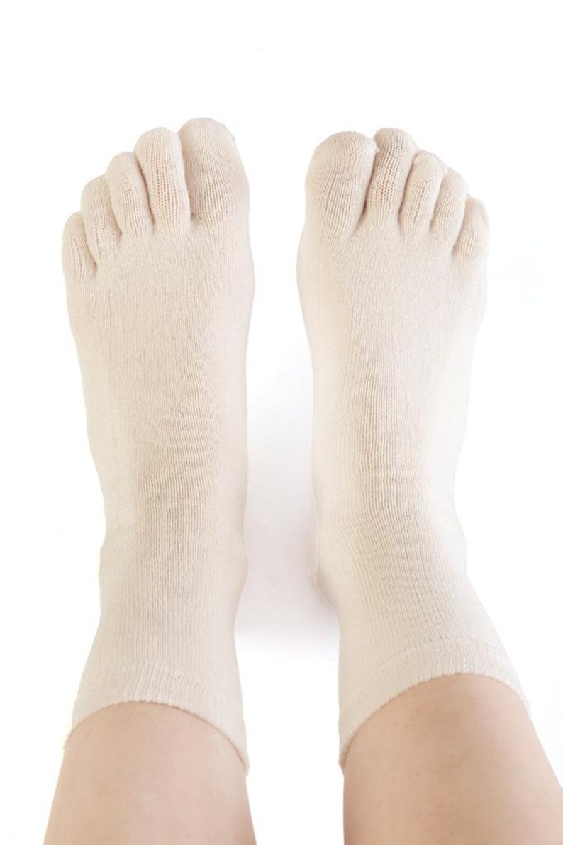 May include: A pair of off-white toe socks with five individual toe compartments. The socks are made of a soft, breathable fabric and are designed to provide comfort and support.
