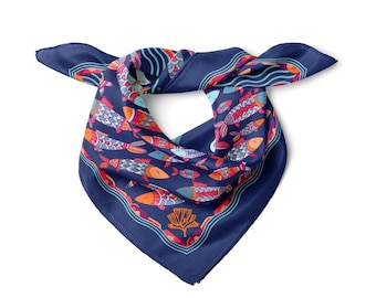 May include: A navy blue square scarf with a repeating pattern of colorful fish in shades of orange, red, and blue. The scarf has a decorative border and is knotted in the center.