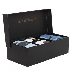 Puede incluir: Una caja negra con el texto dorado "Salt & Vinegar" en la tapa interior. La caja contiene tres pares de calcetines estampados en tonos de azul, negro, blanco y rojo.