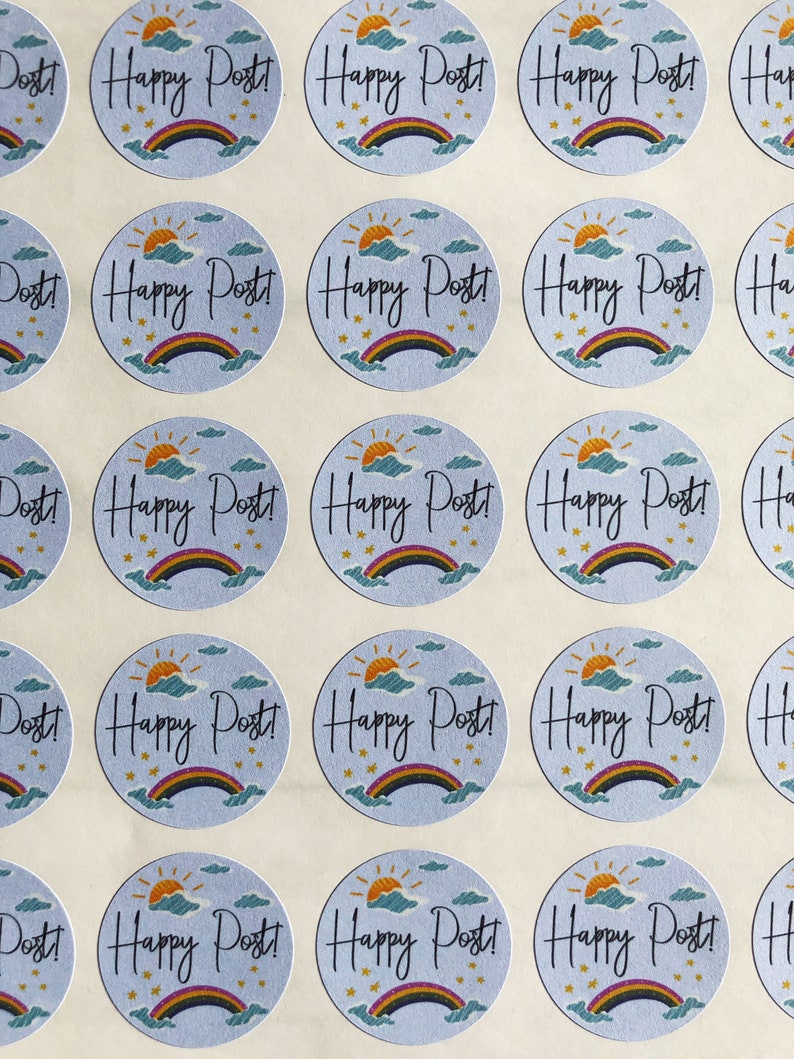以下が含まれることがあります： 水色の背景に「Happy Post!」の文字が筆記体で書かれた丸いステッカー。各ステッカーには虹、太陽、雲のデザインがあります。ステッカーはグリッドパターンで配置されています。
