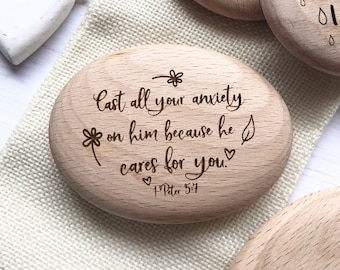 May include: A wooden oval-shaped coaster with the text "Cast all your anxiety on him because he cares for you." and "1 Peter 5:7" engraved on it.