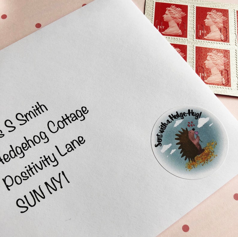 May include: White envelope with address and a round sticker that says "Sent with a Hedge Hug!" featuring a hedgehog illustration. Red postage stamps with a profile of Queen Elizabeth II are in the upper right corner.