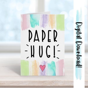 May include: A digital download of a greeting card with a watercolor background in shades of pink, blue, green, and yellow. The card says "PAPER HUG!" in black text with a small pink heart in the center.