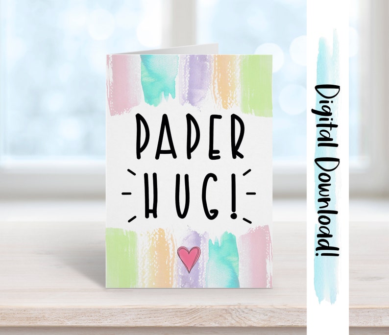May include: A digital download of a greeting card with a watercolor background in shades of pink, blue, green, and yellow. The card says "PAPER HUG!" in black text with a small pink heart in the center.