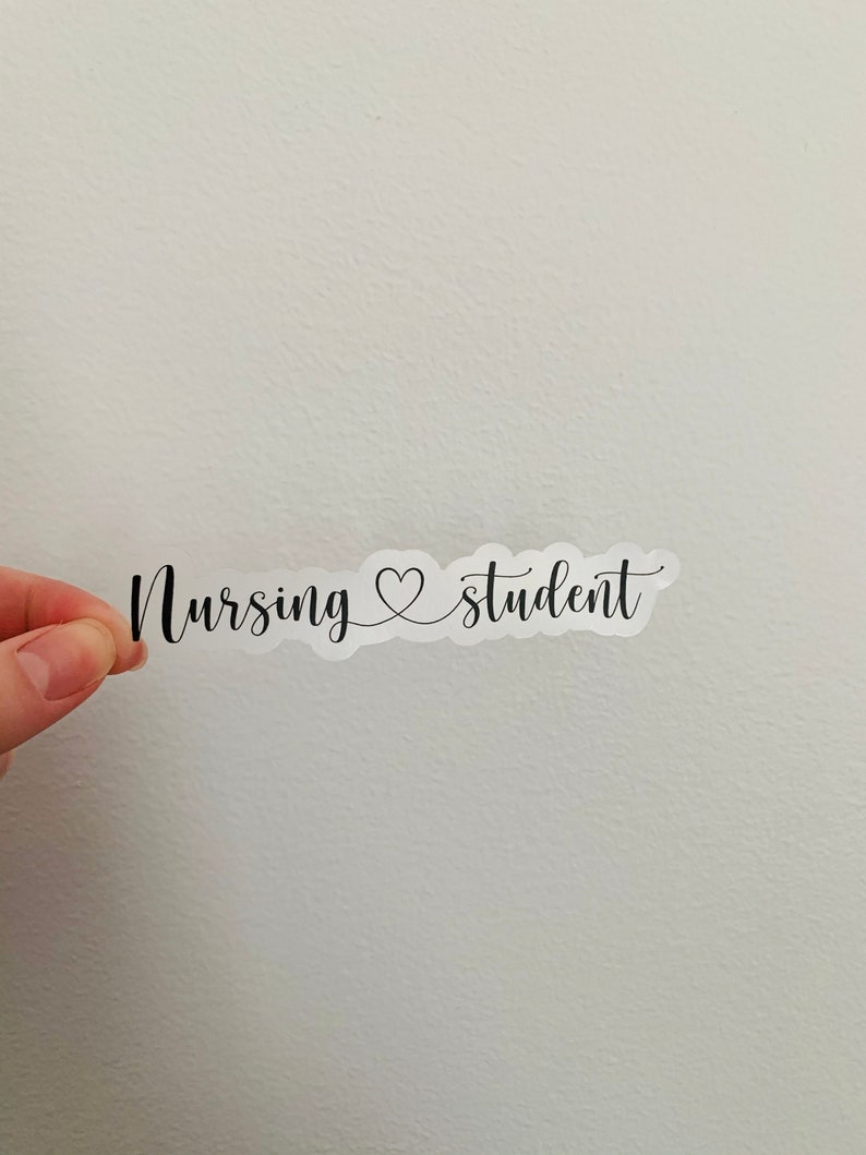K&ouml;nnte beinhalten: Ein wei&szlig;er Aufkleber mit schwarzem Text, der "Nursing &hearts; student" lautet.