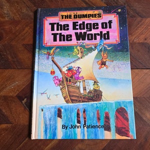 Puede incluir: Portada del libro infantil "The Edge of the World" con una colorida ilustración de un barco y personajes de dibujos animados. El título está en letras grandes y en negrita, y el nombre del autor, John Patience, está en la parte inferior. El libro tiene un diseño vibrante.