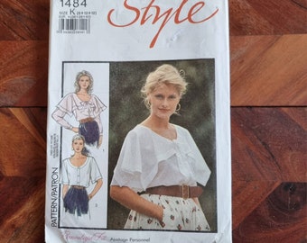 May include: A vintage sewing pattern for a white blouse with a ruffled neckline and long sleeves. The pattern is labeled "Style" and "1484" and includes instructions for sizes 8, 10, and 12.