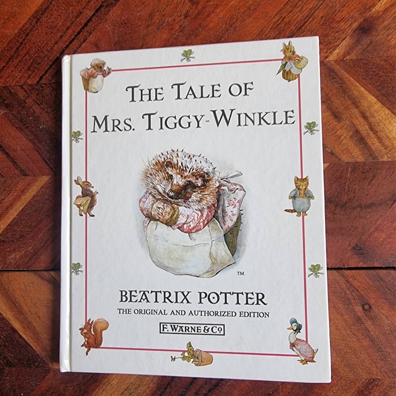 May include: The Tale of Mrs. Tiggy-Winkle book cover featuring a hedgehog wearing a pink and white dress and apron. The book is by Beatrix Potter and is the original and authorised edition published by F. Warne & Co.