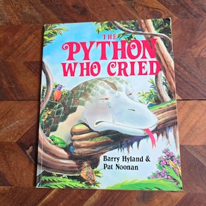 May include: A children's book cover featuring a colourful illustration of a sad python with a tear rolling down its cheek. The title of the book is "The Python Who Cried" and the authors are Barry Hyland & Pat Noonan.