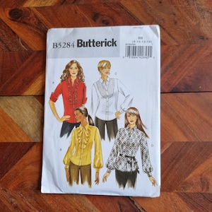 May include: A sewing pattern for four different blouses. The pattern is from Butterick and is for sizes 8-10-12-14. The pattern shows four different women wearing the blouses. The blouses have different styles, including a ruffled blouse, a blouse with a pleated front, and a blouse with a gathered waist.