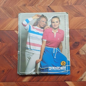 Puede incluir: Folleto de patrones Knitwit con dos mujeres que llevan blusas de punto a rayas y lisas con una falda azul. La portada del folleto incluye el texto "¡Puedo coser eso!" y "Knitwit Clases, telas, patrones".