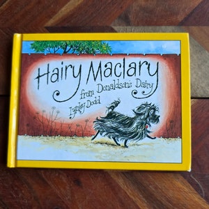 May include: A yellow book cover with the title "Hairy Maclary from Donaldson's Dairy" by Lynley Dodd. The cover features an illustration of a black and white dog running on a path.