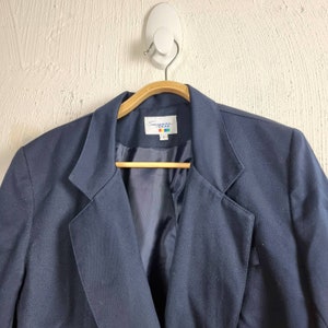 May include: A navy blue blazer with a label that reads "Suzanne Rae" in colourful letters.
