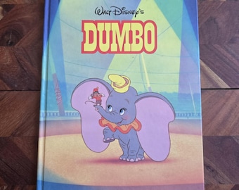 May include: A Big Golden Book featuring Walt Disney's Dumbo. The cover shows Dumbo, a baby elephant with large ears, standing on a stage with a small clown figure on his trunk. The background is a colorful circus tent.