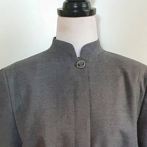 May include: A gray blazer with a mandarin collar and a single button closure.