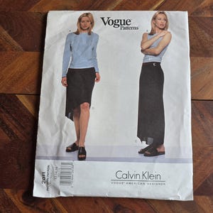 Könnte beinhalten: Vogue Patterns Schnittmuster mit einem Calvin Klein Design. Das Schnittmuster zeigt Illustrationen eines langen Rocks und eines Oberteils. Die Größe des Schnittmusters ist 12, 14 und 16. Die Logos von Vogue Patterns und Calvin Klein sind sichtbar.