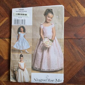 Puede incluir: Un sobre de patrón de costura Vogue for Me, número 7681, con ilustraciones de tres vestidos largos diferentes para niños. Los vestidos tienen mangas cortas, escotes redondos y faldas amplias. El patrón incluye las tallas 6, 7 y 8.