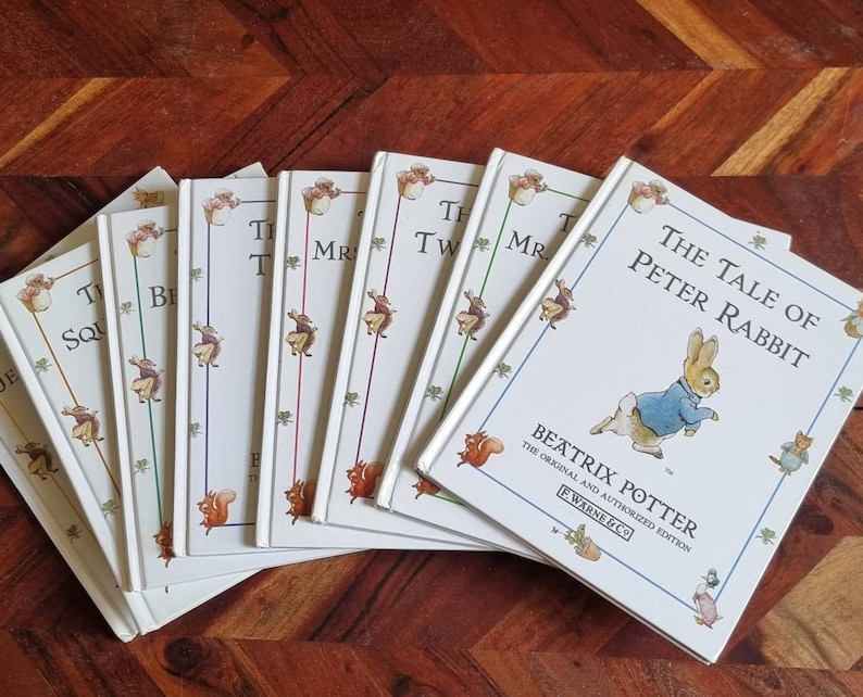 May include: A collection of eight vintage children's books featuring Beatrix Potter characters. The books are in white covers with colourful illustrations and titles like "The Tale of Peter Rabbit", "The Tale of Squirrel Nutkin", "The Tale of Mr. Tod", and "The Tale of Two Bad Mice".