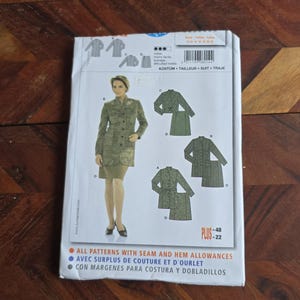 Può includere: Un pacchetto di modelli di cucito con una donna in un completo verde. Il pacchetto include illustrazioni del design del completo, con testo in più lingue, tra cui "KOSTÜM TAILLEUR SUIT TRAJE" e "ALL PATTERNS WITH SEAM AND HEM ALLOWANCES".