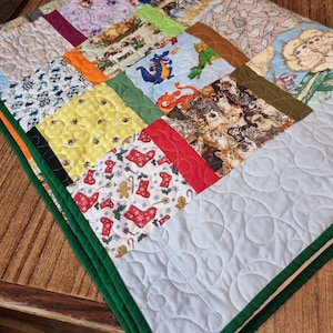 Puede incluir: Una colcha de retazos con una variedad de telas y patrones coloridos, incluyendo una tela azul y verde con un diseño de dragón, una tela roja y blanca con un diseño de calcetín de Navidad y una tela amarilla y blanca con un patrón a cuadros.