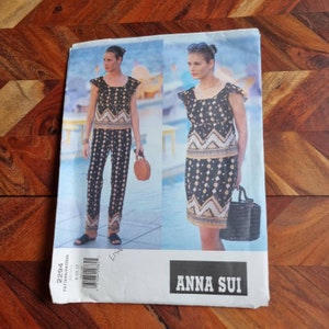 May include: A sewing pattern for a black and gold dress and pants set with a geometric print. The pattern is by Anna Sui and is for sizes 8-18.