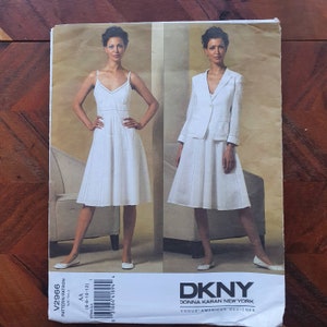 Pode incluir: Um padrão de costura vintage com dois conjuntos brancos: um vestido com alças finas e um fato de saia com blazer. O padrão está rotulado como "V2966" e inclui os logotipos DKNY e Vogue American Designer.