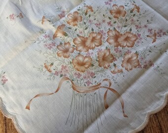 Könnte beinhalten: Eine weiße Tischdecke mit einem braunen Blumendesign. Die Blumen sind in einem Strauß mit einem braunen Band angeordnet.