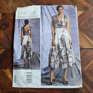 May include: A vintage dressmaking pattern with a black and white architectural print on the skirt. The pattern is labelled "Lialia by Julia Alarcon" and includes size details. The dress has a V-neck and cap sleeves.