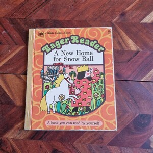 May include: A vintage children's book titled "Eager Reader: A New Home for Snow Ball" with a colorful illustration of a king and a white horse on the cover. The book is part of the Little Golden Book series.