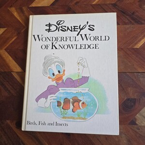 May include: A vintage children's book titled "Disney's Wonderful World of Knowledge: Birds, Fish and Insects". The cover features a cartoon illustration of a female duck character feeding fish in a bowl.