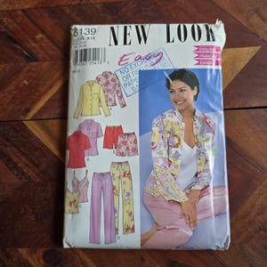 Puede incluir: Un sobre de patrón de costura New Look con ilustraciones de pijamas y ropa de dormir. La portada muestra a una mujer con una camisa de pijama con estampado floral y pantalones rosas. El sobre incluye el texto "NEW LOOK" y "ENGLISH, FRANÇAIS, ESPAÑOL".