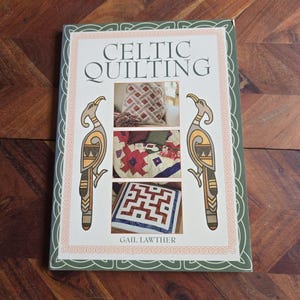 May include: A book titled "Celtic Quilting" by Gail Lawther. The cover features a green Celtic knot border with stylised birds and images of quilts with geometric patterns.