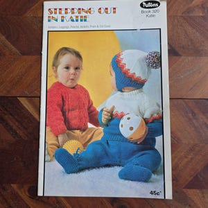 May include: A knitting pattern book cover featuring two babies wearing knitted clothing. The book is titled "Stepping Out in Katie" and is for Patons Book 320. The babies are wearing a red and white knitted sweater and a blue and white knitted sweater with a matching hat.