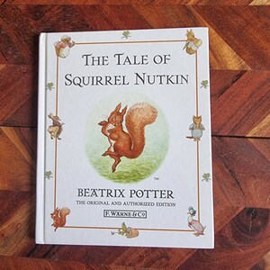 May include: A white book cover featuring an illustration of a red squirrel. The title is "The Tale of Squirrel Nutkin" by Beatrix Potter. This is the original and authorised edition.
