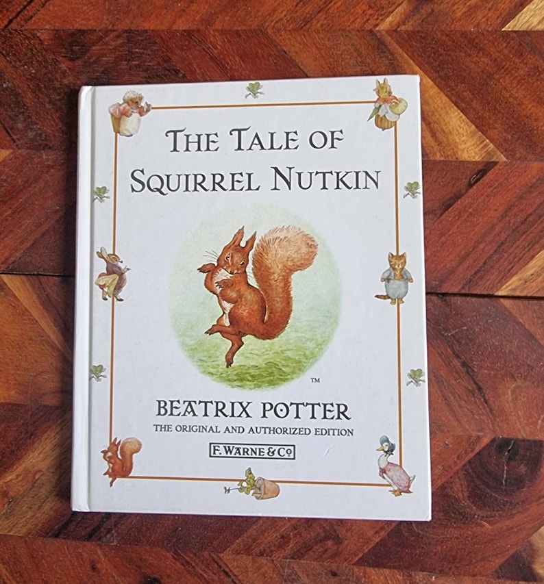 May include: A white book cover featuring an illustration of a red squirrel. The title is "The Tale of Squirrel Nutkin" by Beatrix Potter. This is the original and authorised edition.