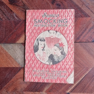 Puede incluir: Un libro de instrucciones vintage rojo y blanco para el smocking, con ilustraciones de tres mujeres con prendas smock. El título del libro es "Semco Smocking Instruction Book" e incluye el texto "Also Bulgarian Smocking, Laid Pleating, Lingerie Embroidery, Fagoting".