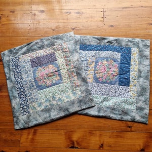 May include: Two blue and white patchwork pillow covers with floral designs. The pillow covers are made of a soft, cotton fabric and have a subtle distressed look.