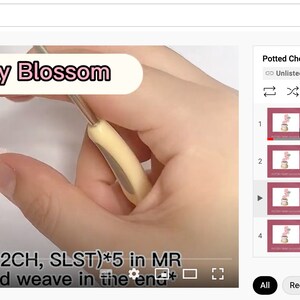 K&ouml;nnte beinhalten: Ein YouTube-Video mit dem Titel "Cherry Blossom" zeigt eine Nahaufnahme von H&auml;kelarbeiten. Das Video enth&auml;lt Textanweisungen und eine Liste verwandter Videos, darunter "Pot", "Leaves" und "Assembly".