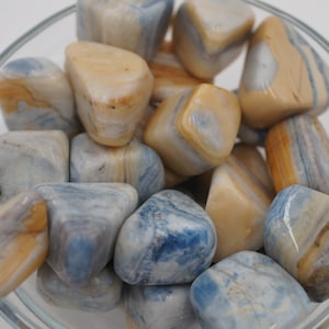 May include: A bowl of blue and brown banded tumbled stones. The stones are smooth and polished.