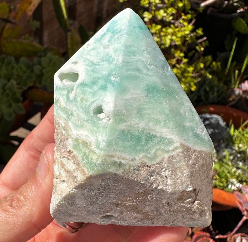 May include: A green and white celestite crystal point with a rough, natural base. The crystal has a layered, banded appearance and is a popular choice for crystal healing and meditation.