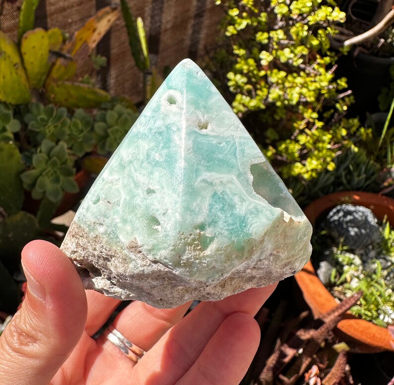 May include: A light green, naturally formed, crystal pyramid with a rough, textured surface.