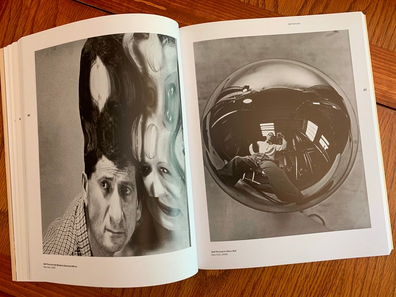 May include: A black and white photograph of a man with a distorted reflection of his face above his head. The reflection is created by a curved mirror. The man is looking at the camera with a serious expression. The photograph is titled "Self Portrait with Model's Distorted Mirror".