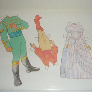 May include: Paper doll set featuring a green and gold uniform, a pair of orange pants and top, and a white wedding dress. The illustrations are outlined in brown and have tabs for cutting out the figures.