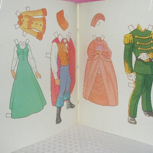 May include: An open book featuring paper dolls with various outfits. The outfits include a green dress, a yellow coat, a prince's attire with a red cape, a pink gown, and a green military uniform. The paper dolls are designed with tabs for easy removal.