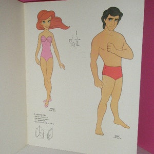 May include: A page from a vintage paper doll book featuring illustrations of Ariel and Eric. Ariel is in a pink swimsuit, and Eric is in red swim trunks. The characters are drawn in a cartoon style.