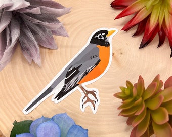 Puede incluir: Una pegatina de un petirrojo con la espalda gris, el vientre blanco y el pecho naranja. El pájaro está posado en una rama con las alas extendidas.